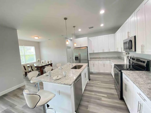 kitchen featuring white cabinetry, an island with sink, light wood-type flooring, and appliances with stainless steel finishes