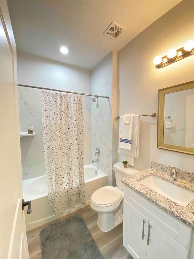 full bathroom with hardwood / wood-style floors, vanity, and shower / tub combo