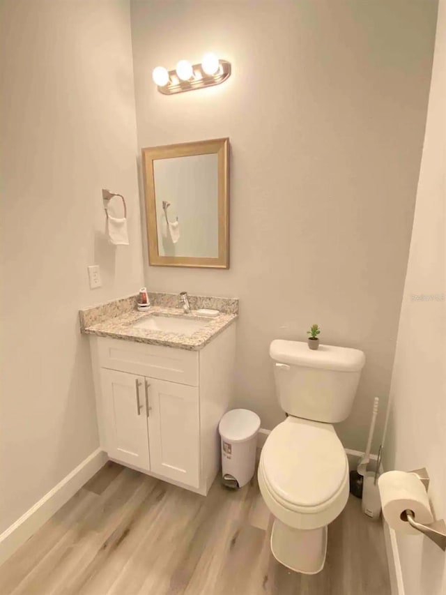 bathroom featuring vanity, wood-type flooring, and toilet