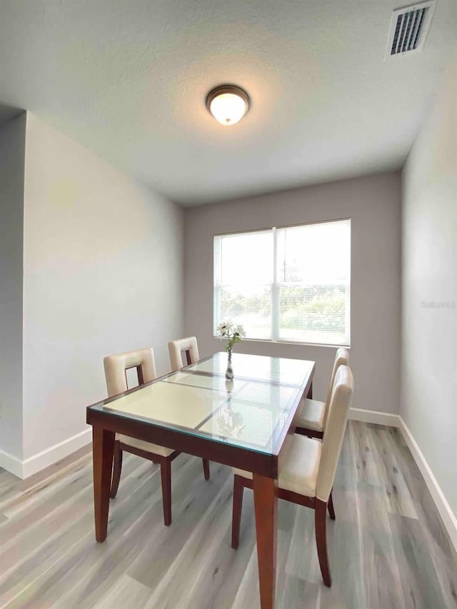 dining area featuring light hardwood / wood-style floors and a textured ceiling