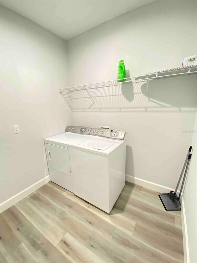 clothes washing area featuring light wood-type flooring and separate washer and dryer