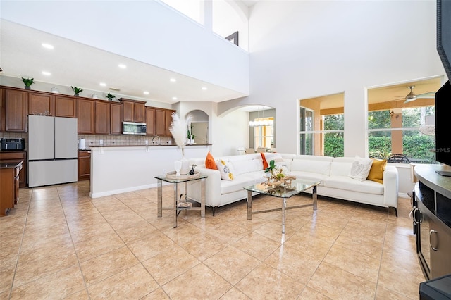 living room featuring ceiling fan, light tile patterned floors, and a high ceiling