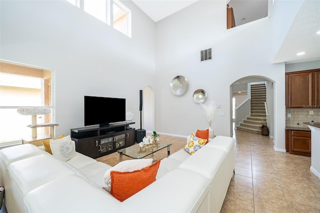 living room featuring light tile patterned flooring and a towering ceiling