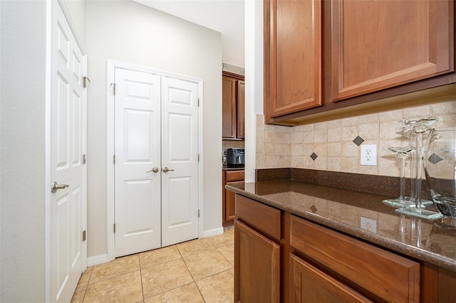 kitchen with dark stone counters, light tile patterned floors, and tasteful backsplash