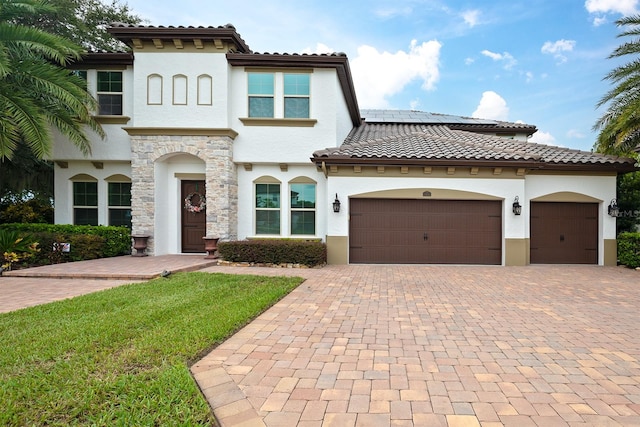 mediterranean / spanish home featuring a garage and a front lawn