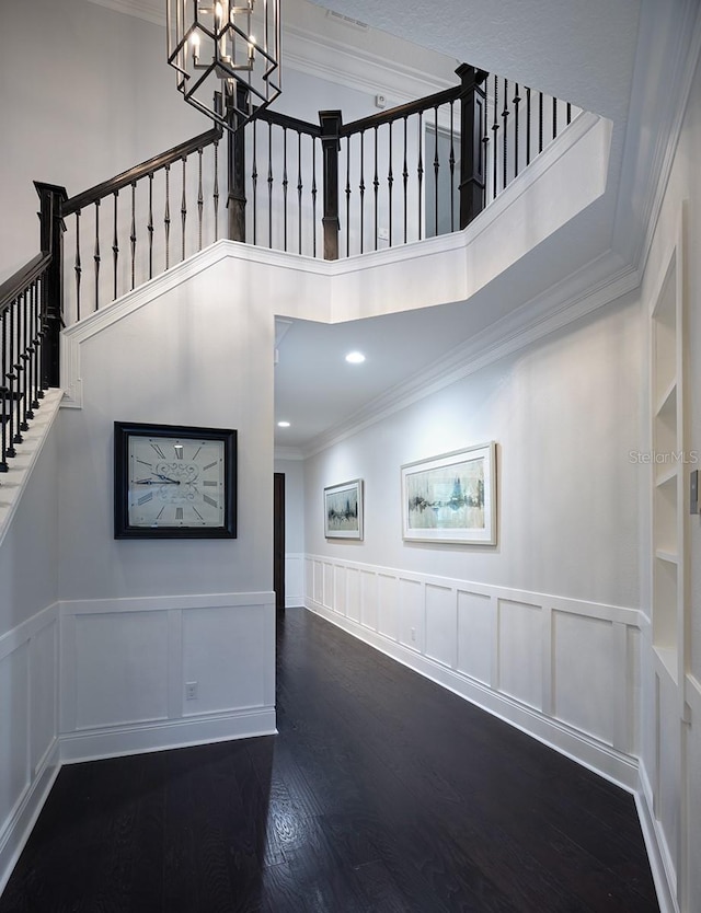 interior space with ornamental molding, built in shelves, hardwood / wood-style flooring, and an inviting chandelier