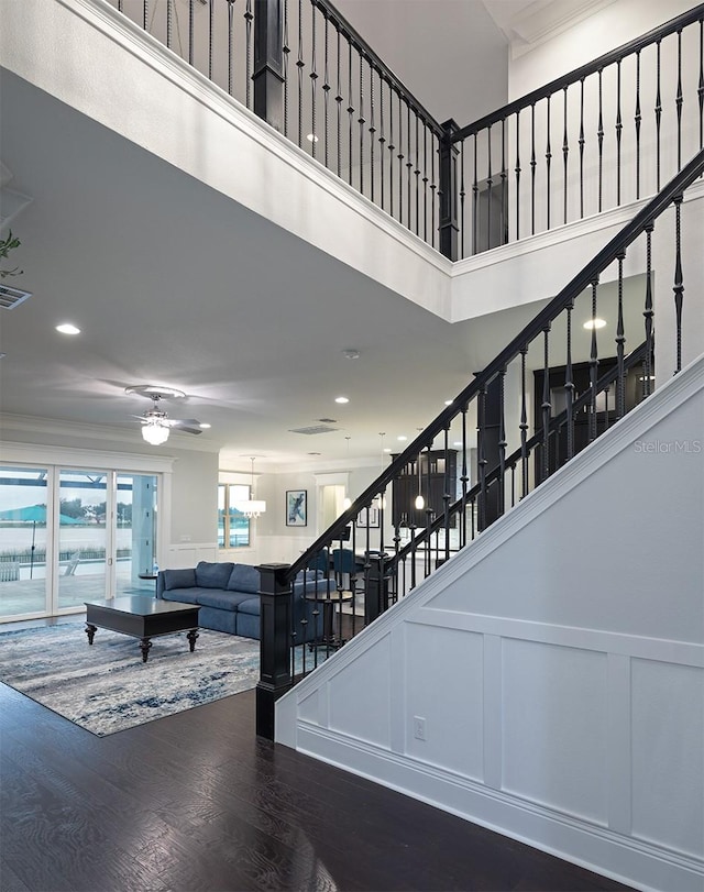 stairs with a high ceiling, ceiling fan, and hardwood / wood-style floors