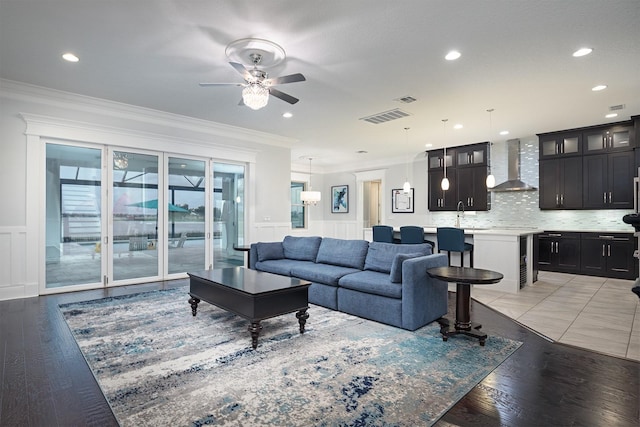 living room featuring light hardwood / wood-style floors, wine cooler, crown molding, ceiling fan, and sink