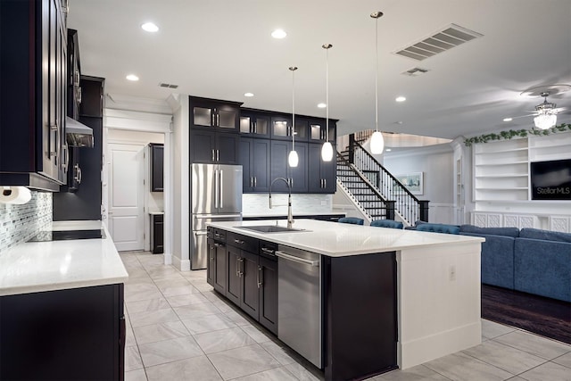 kitchen with a kitchen island with sink, sink, hanging light fixtures, appliances with stainless steel finishes, and ceiling fan