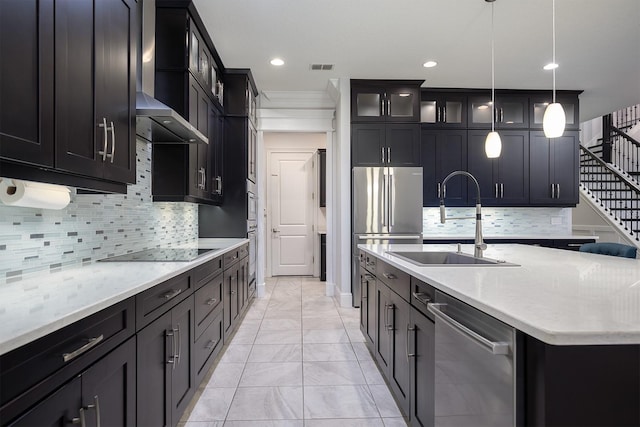 kitchen with pendant lighting, sink, tasteful backsplash, wall chimney range hood, and appliances with stainless steel finishes