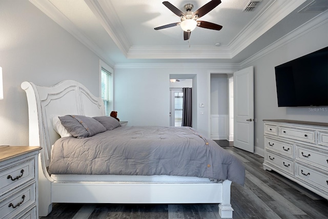 bedroom featuring ornamental molding, a tray ceiling, ceiling fan, and dark wood-type flooring