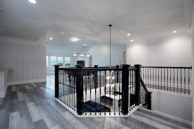 hallway featuring wood-type flooring, lofted ceiling, crown molding, and a notable chandelier