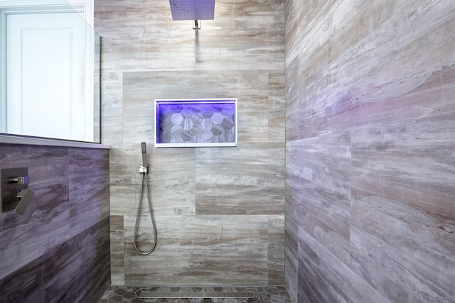 bathroom with a tile shower and tile walls