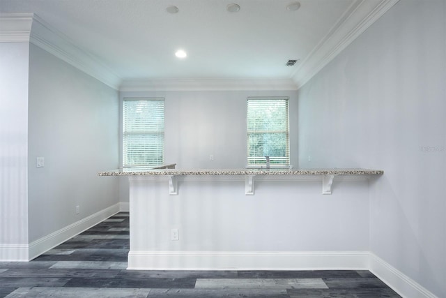 kitchen featuring a breakfast bar, ornamental molding, dark hardwood / wood-style floors, and a wealth of natural light