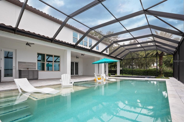 view of swimming pool with glass enclosure, ceiling fan, and a patio area