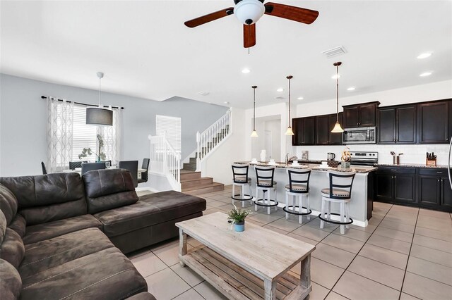 living room featuring light tile patterned flooring, sink, and ceiling fan