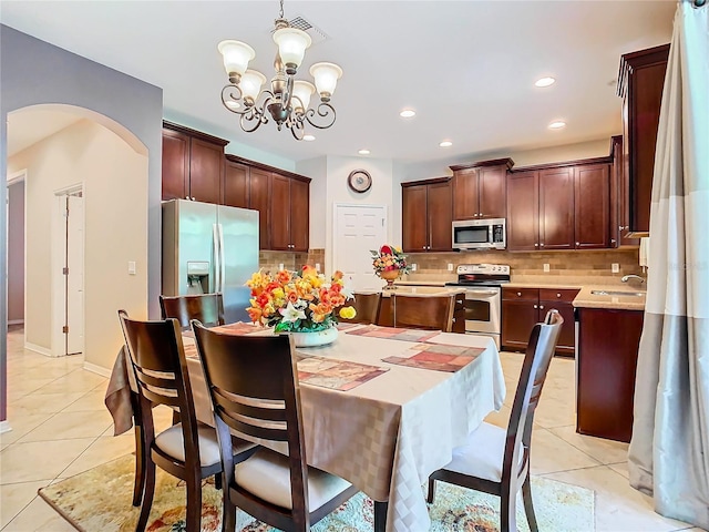 kitchen featuring pendant lighting, a notable chandelier, appliances with stainless steel finishes, and light tile patterned flooring