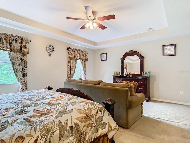 bedroom with ceiling fan, a raised ceiling, and carpet flooring