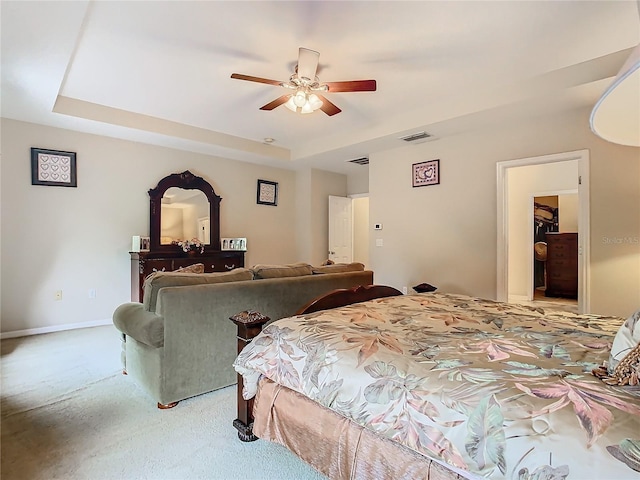 carpeted bedroom with a raised ceiling and ceiling fan