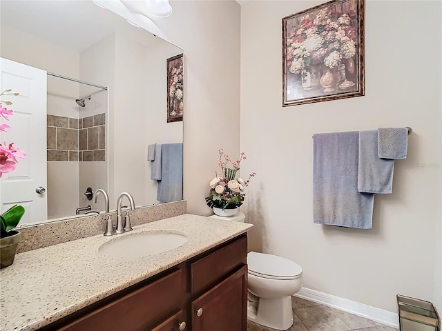 bathroom with a tile shower, vanity, tile patterned flooring, and toilet