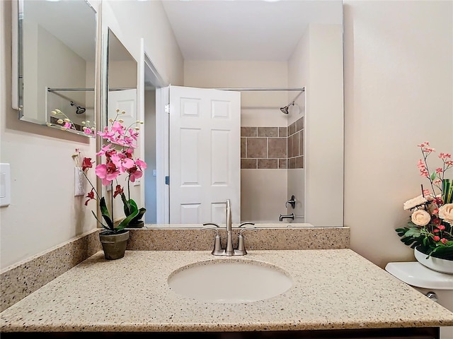 bathroom featuring a tile shower, vanity, and toilet