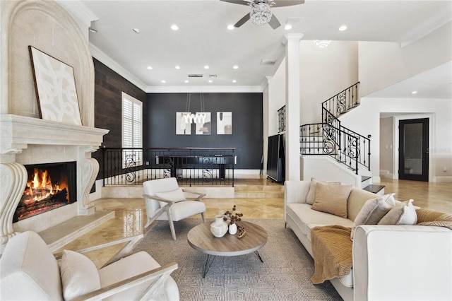 living room featuring ceiling fan, ornamental molding, and a tiled fireplace