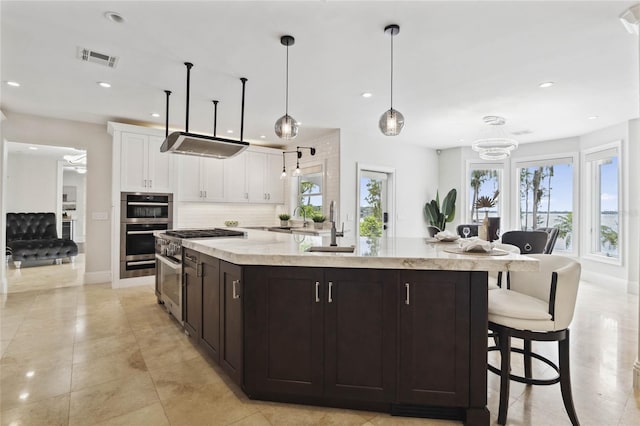 kitchen featuring a spacious island, white cabinetry, pendant lighting, and a healthy amount of sunlight