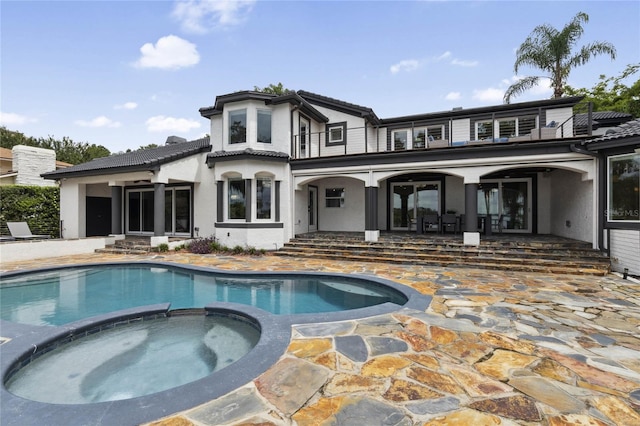 rear view of house featuring a patio area and a pool with hot tub