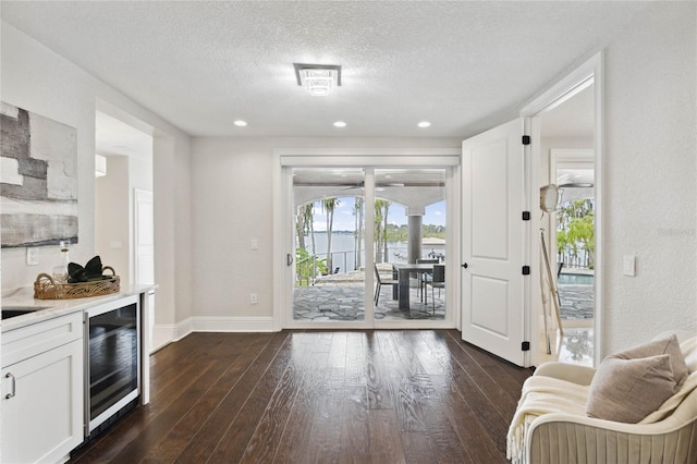 kitchen featuring a textured ceiling, wine cooler, white cabinetry, and dark hardwood / wood-style floors