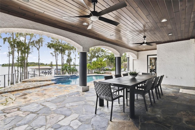 view of patio featuring a swimming pool with hot tub and a water view