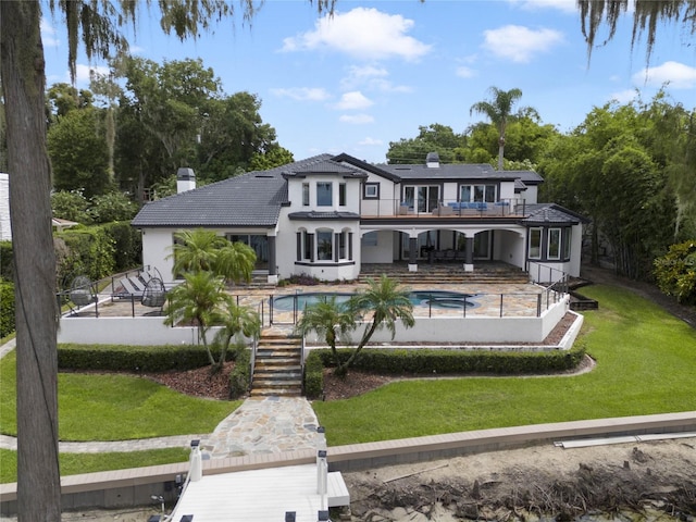 rear view of property with a balcony, a patio area, and a lawn