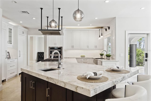 kitchen featuring white cabinets, sink, and hanging light fixtures