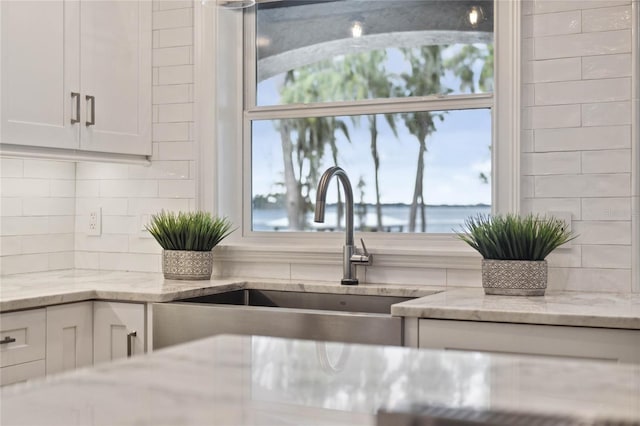 kitchen with white cabinets, a water view, and plenty of natural light