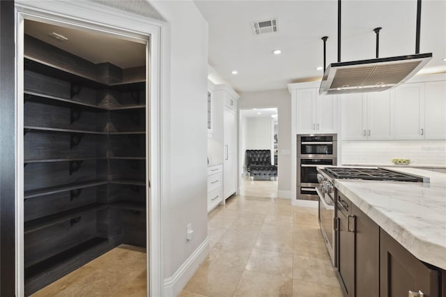 kitchen featuring light stone countertops, decorative backsplash, stainless steel appliances, white cabinetry, and hanging light fixtures