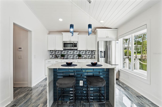 kitchen with lofted ceiling, stainless steel appliances, white cabinetry, tasteful backsplash, and a kitchen bar