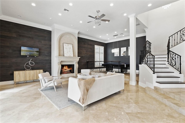 living area featuring visible vents, a lit fireplace, an accent wall, and crown molding