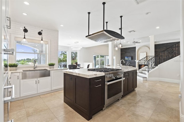 kitchen featuring light stone countertops, a sink, high end stove, white cabinets, and dark brown cabinets