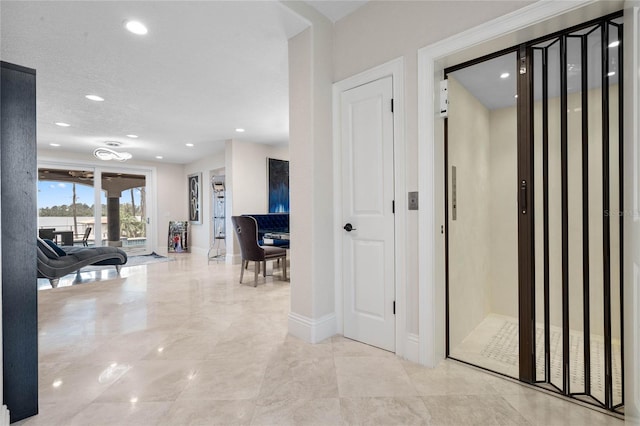 corridor with elevator, recessed lighting, and baseboards