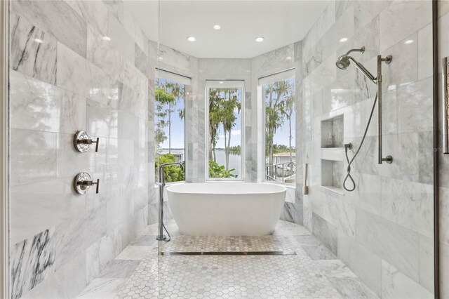 full bath featuring tile walls, a freestanding tub, and walk in shower