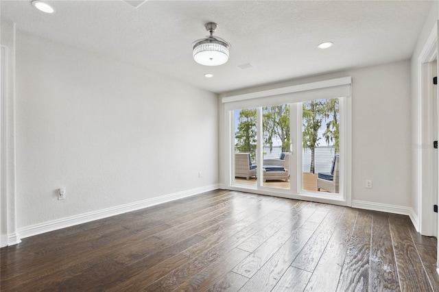 unfurnished room with recessed lighting, a textured ceiling, dark wood-type flooring, and baseboards