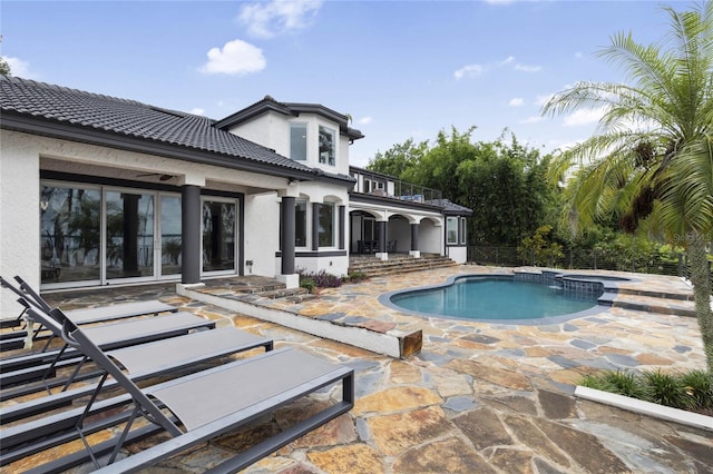 back of house featuring stucco siding, a tile roof, a pool with connected hot tub, a patio, and a balcony