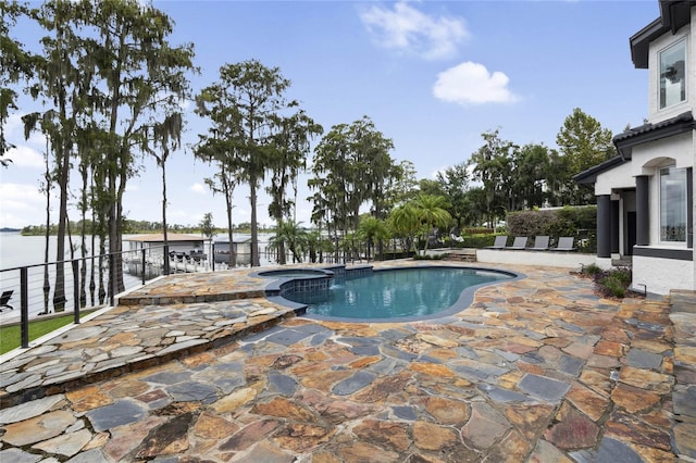 view of swimming pool with a patio, a water view, and a pool with connected hot tub