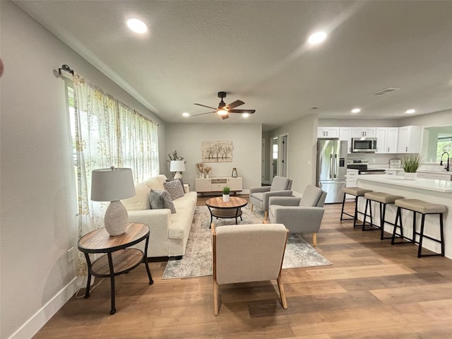 living room with a textured ceiling, a wealth of natural light, ceiling fan, and light hardwood / wood-style floors