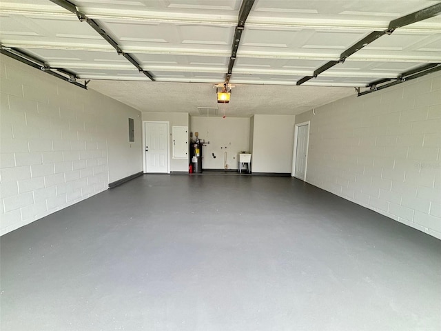 garage with a garage door opener, electric panel, and sink