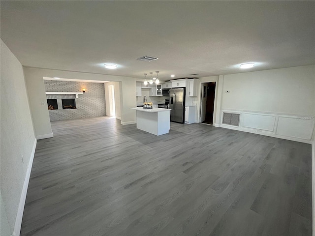 unfurnished living room featuring a brick fireplace, hardwood / wood-style floors, a chandelier, brick wall, and sink