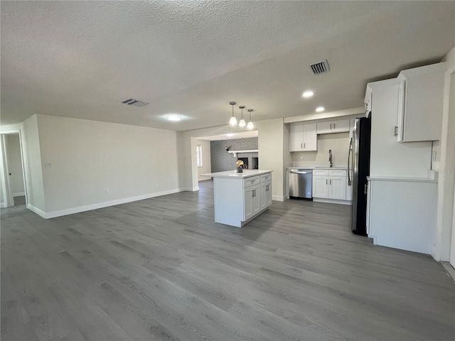 kitchen featuring pendant lighting, stainless steel appliances, light hardwood / wood-style flooring, and white cabinets