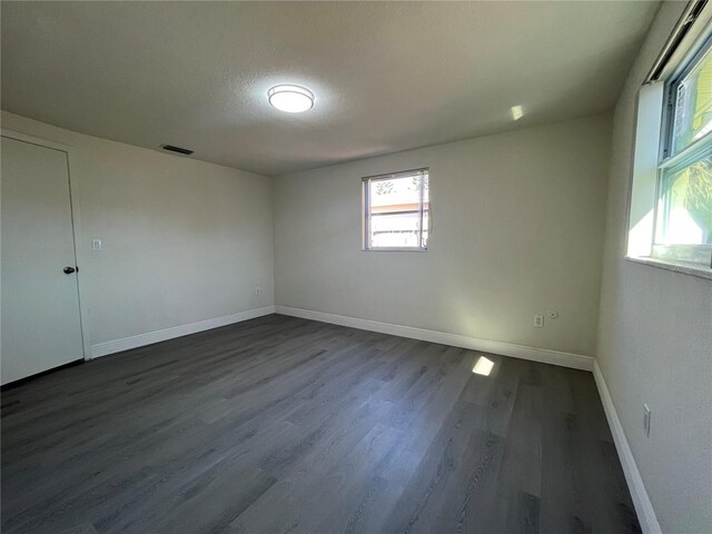 spare room featuring dark wood-type flooring and a textured ceiling