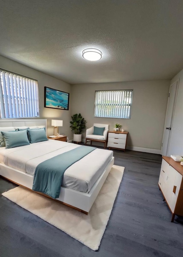 bedroom with multiple windows, a textured ceiling, and dark hardwood / wood-style flooring