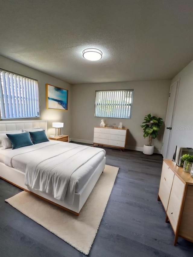 bedroom featuring multiple windows, dark hardwood / wood-style flooring, and a textured ceiling