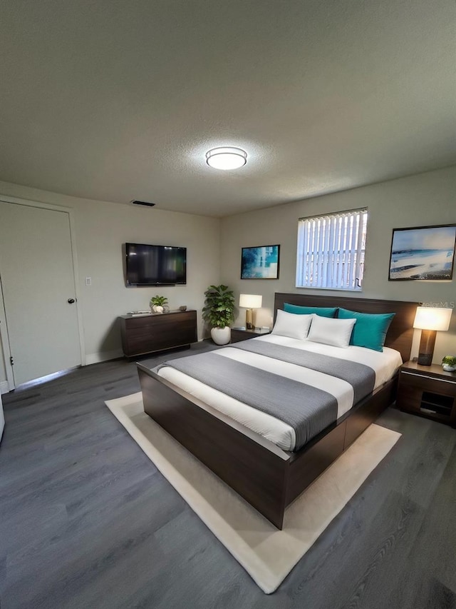 bedroom featuring a textured ceiling and dark hardwood / wood-style flooring